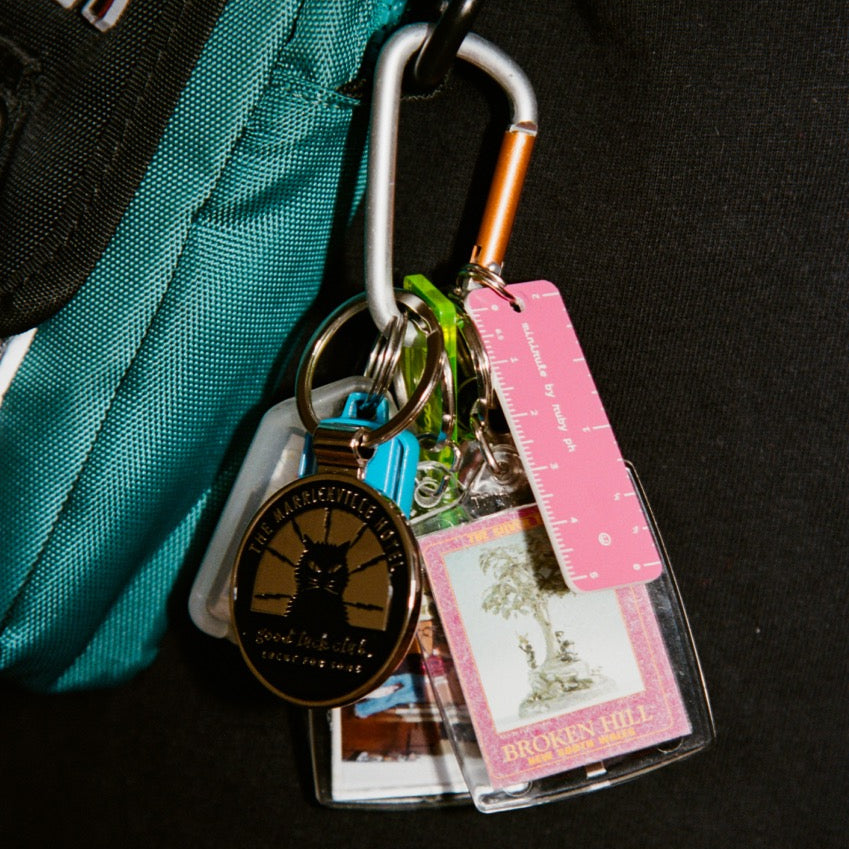 Keychain with various tags and a badge holder attached to a teal bag on a black background