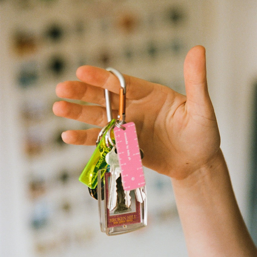 Hand holding a keychain with pink tag against a blurred background