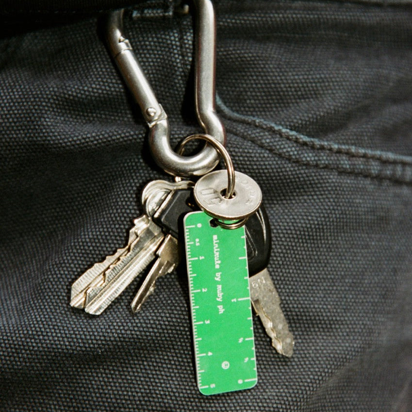 Keychain with keys and a green ruler attached to a black bag.