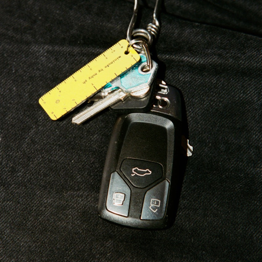 Keychain with car key and remote control attached to a dark fabric surface