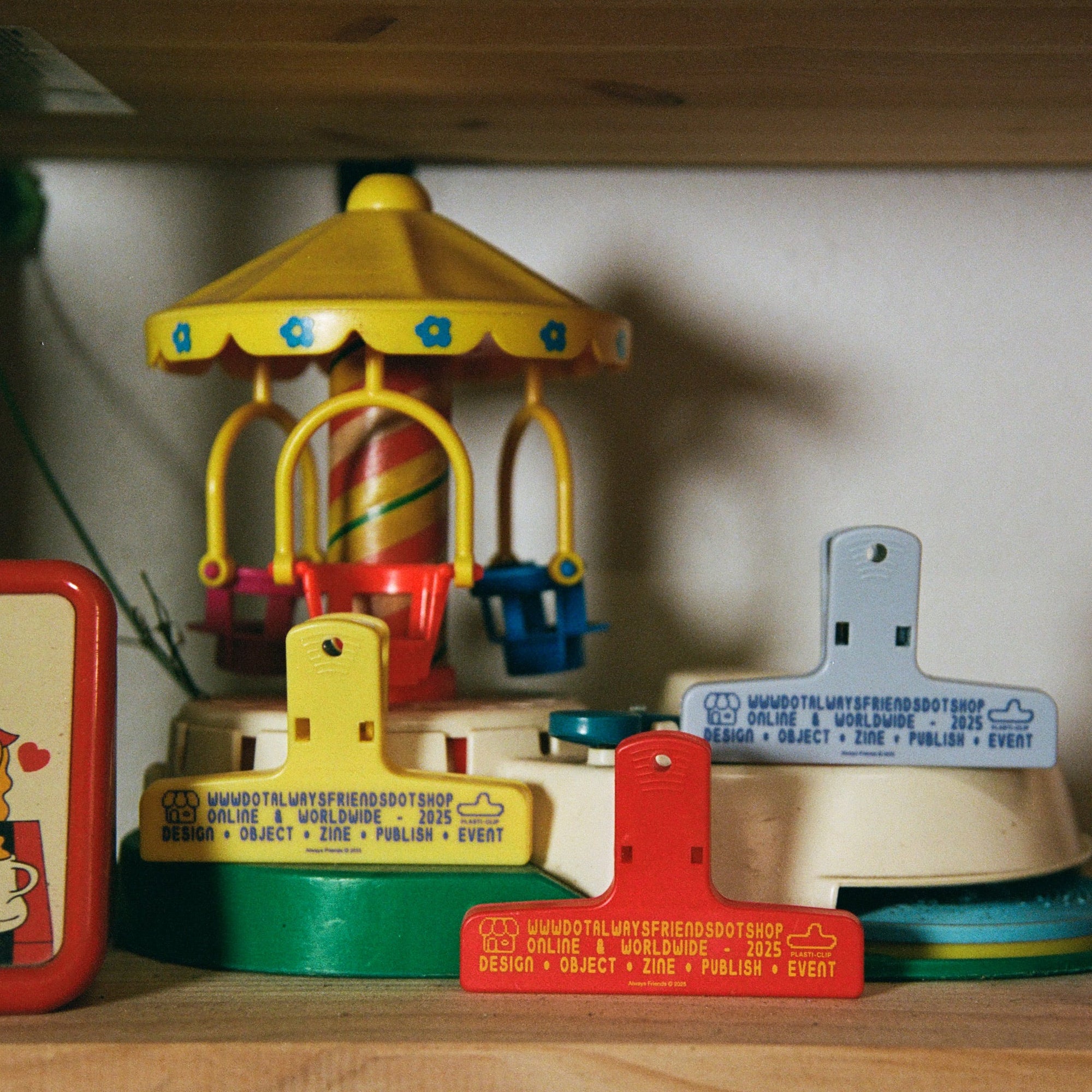 Collection of vintage toys including a small carousel and clock on a wooden shelf.
