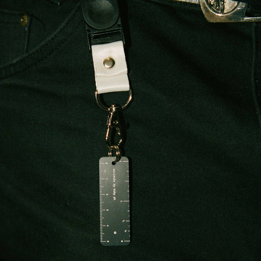 Pentax camera strap with a keychain attached to dark pants