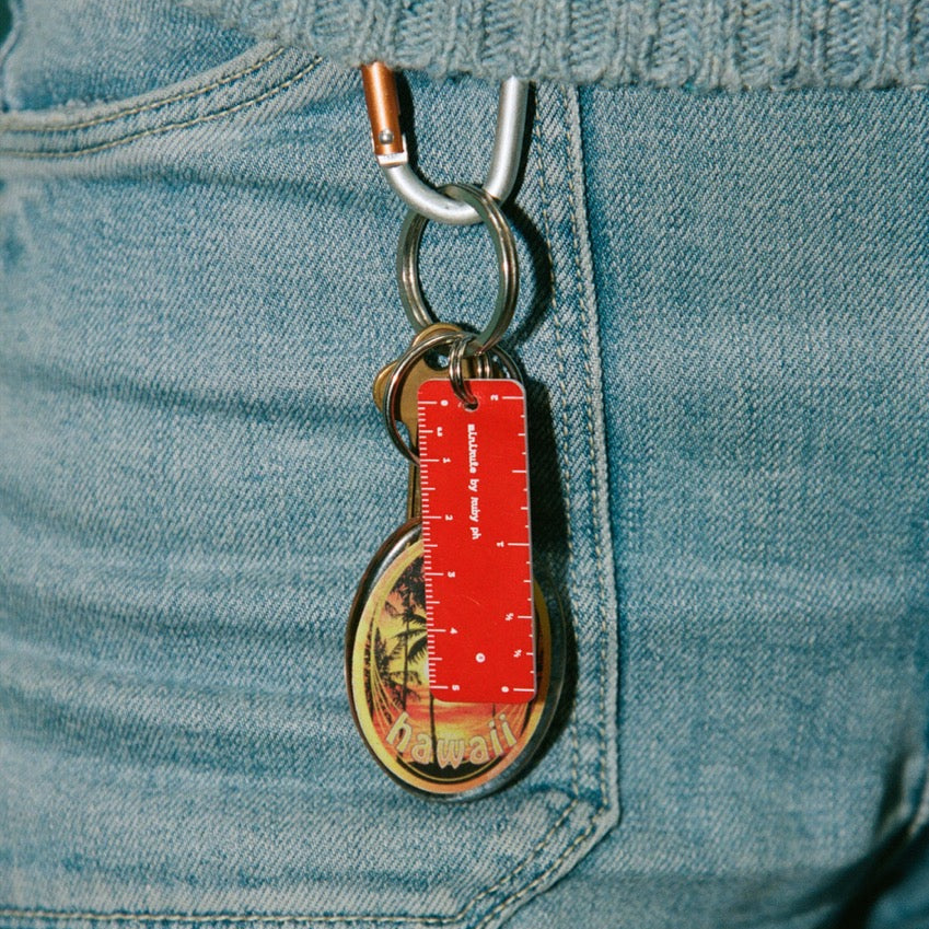 Keychain with a red tag attached to a blue denim pocket.